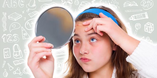 A school girl with a mirror, looking at a pimple on her forehead